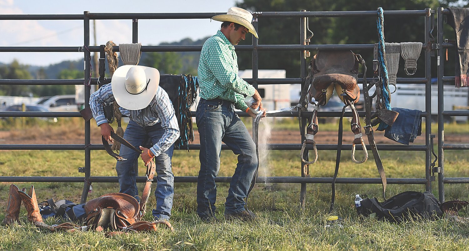 Press Enterprise/Jimmy May.Saddle bronc riders Kiowa Tempest, left, and Raymond Hostetler prepare their saddles before riding Thursday night in the Benton Rodeo.